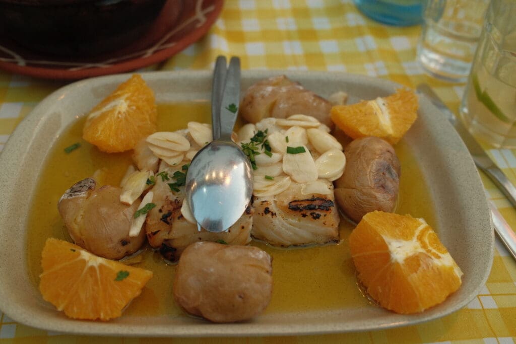 Traditional Portuguese seafood dish served with potatoes and fresh orange slices at a local restaurant.