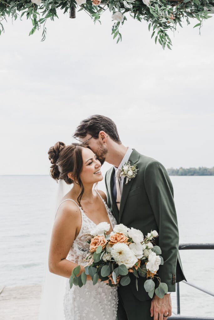 Bride and groom sharing a quiet moment by the waterfront following their wedding ceremony at Waupoos Estates Winery.