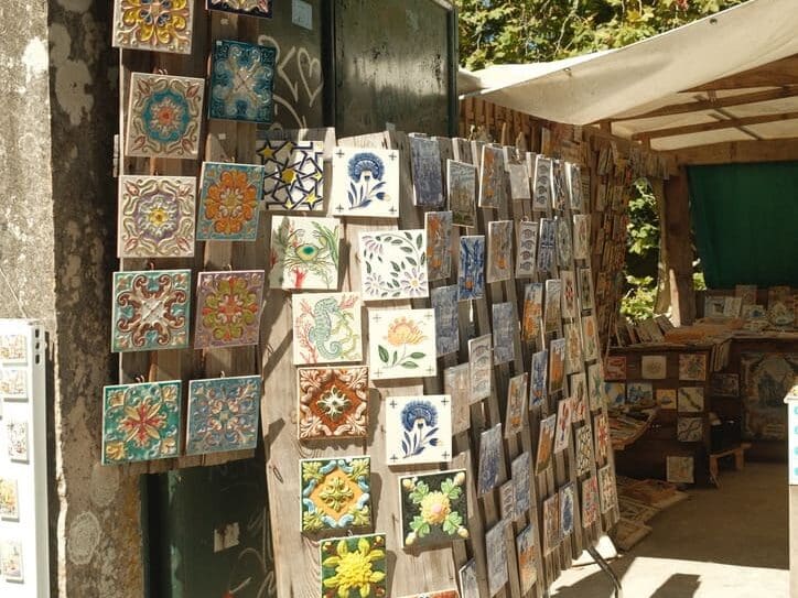Traditional hand-painted Portuguese ceramic tiles displayed at a local artisan market, featuring colorful floral and geometric designs inspired by Portugal's rich cultural heritage.