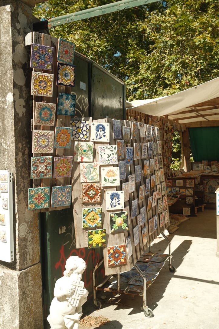 Traditional hand-painted Portuguese ceramic tiles displayed at a local artisan market, featuring colorful floral and geometric designs inspired by Portugal's rich cultural heritage.