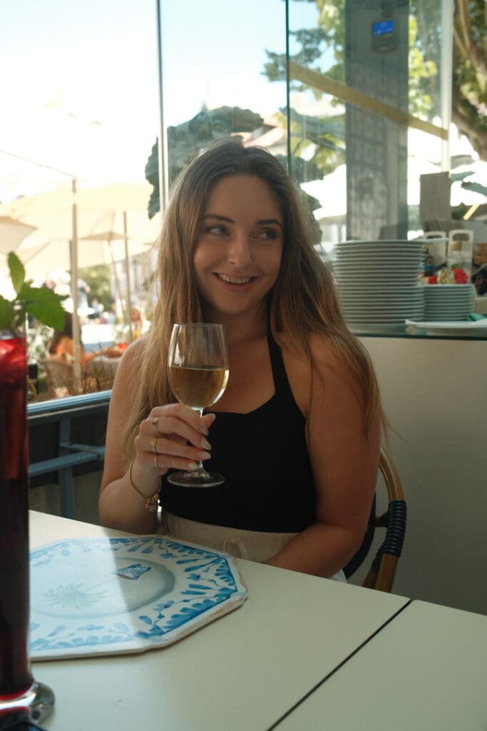 A woman enjoying a glass of wine at a restaurant while exploring Porto, Portugal.