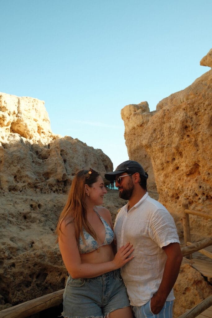 A couple standing among the golden limestone cliffs of the Algarve coastline, enjoying the scenic rock formations and ocean views.