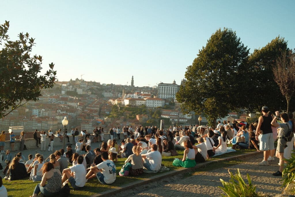 People gathered on the hillside at Jardim do Morro in Porto, Portugal, watching the sunset over the city.