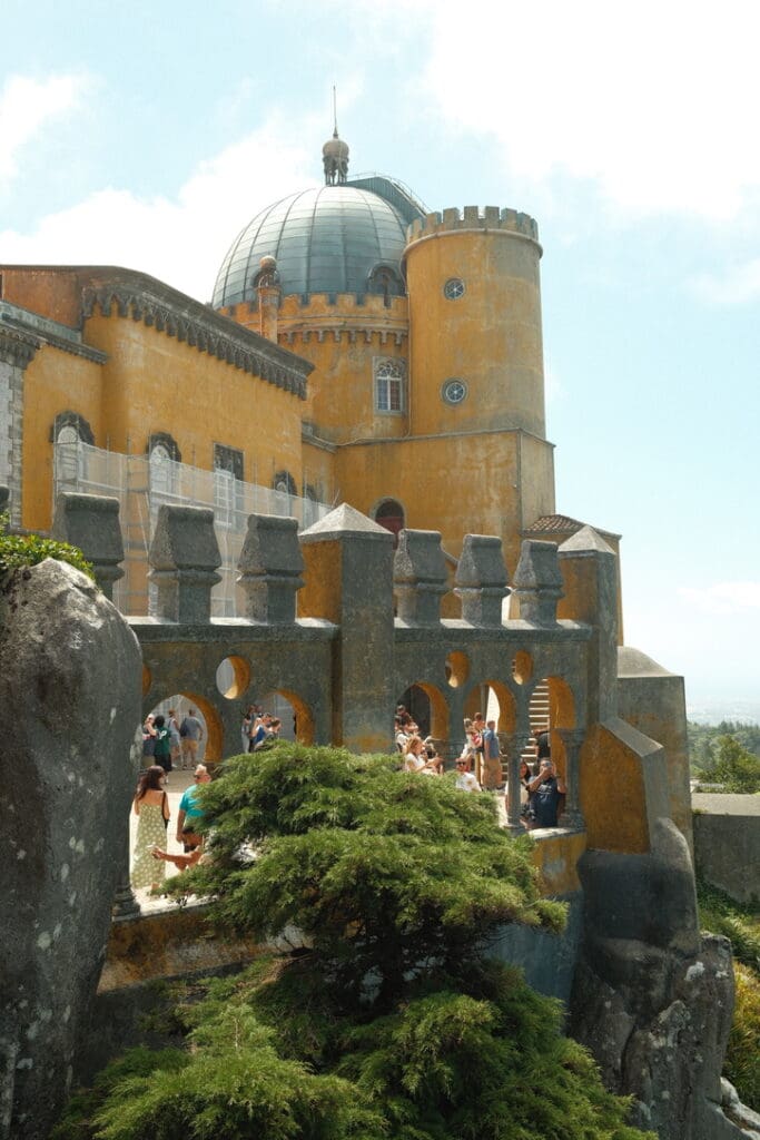 Colorful view of Pena Palace in Sintra, Portugal, perched on a hilltop overlooking the surrounding landscape.