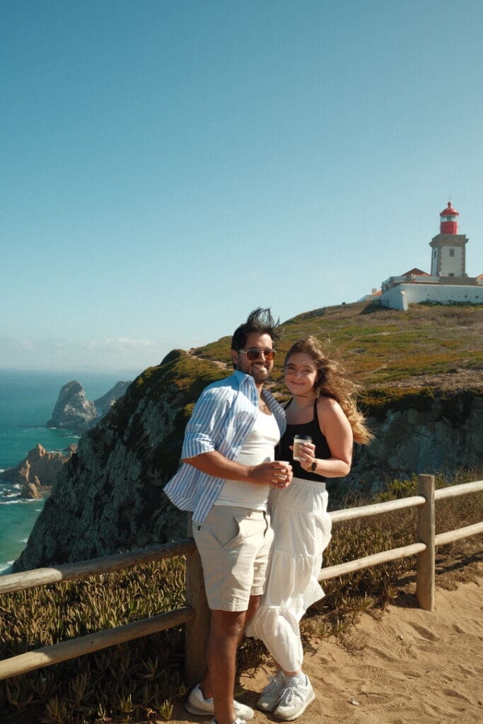 A couple posing at Cabo da Roca, the westernmost point of mainland Europe, with dramatic coastal cliffs in the background.