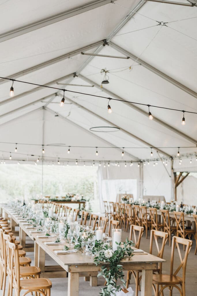 Wedding reception tent set with long tables, elegant florals, and string lights at Waupoos Estates Winery in Prince Edward County.