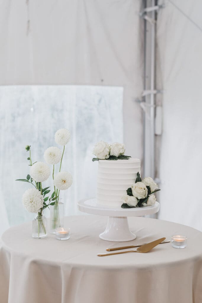 Minimalist wedding cake display featuring white florals and elegant reception décor at Waupoos Estates Winery.
