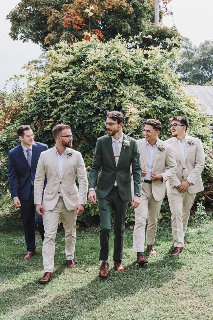 Groom and groomsmen walking together through the vineyard grounds at Waupoos Estates Winery before the wedding ceremony.