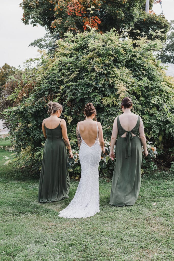 Bride standing with her bridesmaids in matching green dresses surrounded by vineyard greenery at Waupoos Estates Winery.